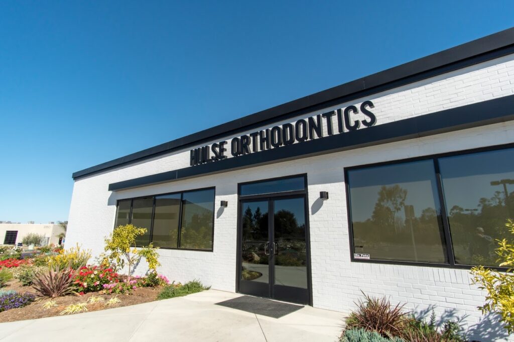 White brick exterior of the Hulse Orthodontics office with its sign and front doors, Hulse Orthodontics, Carlsbad CA